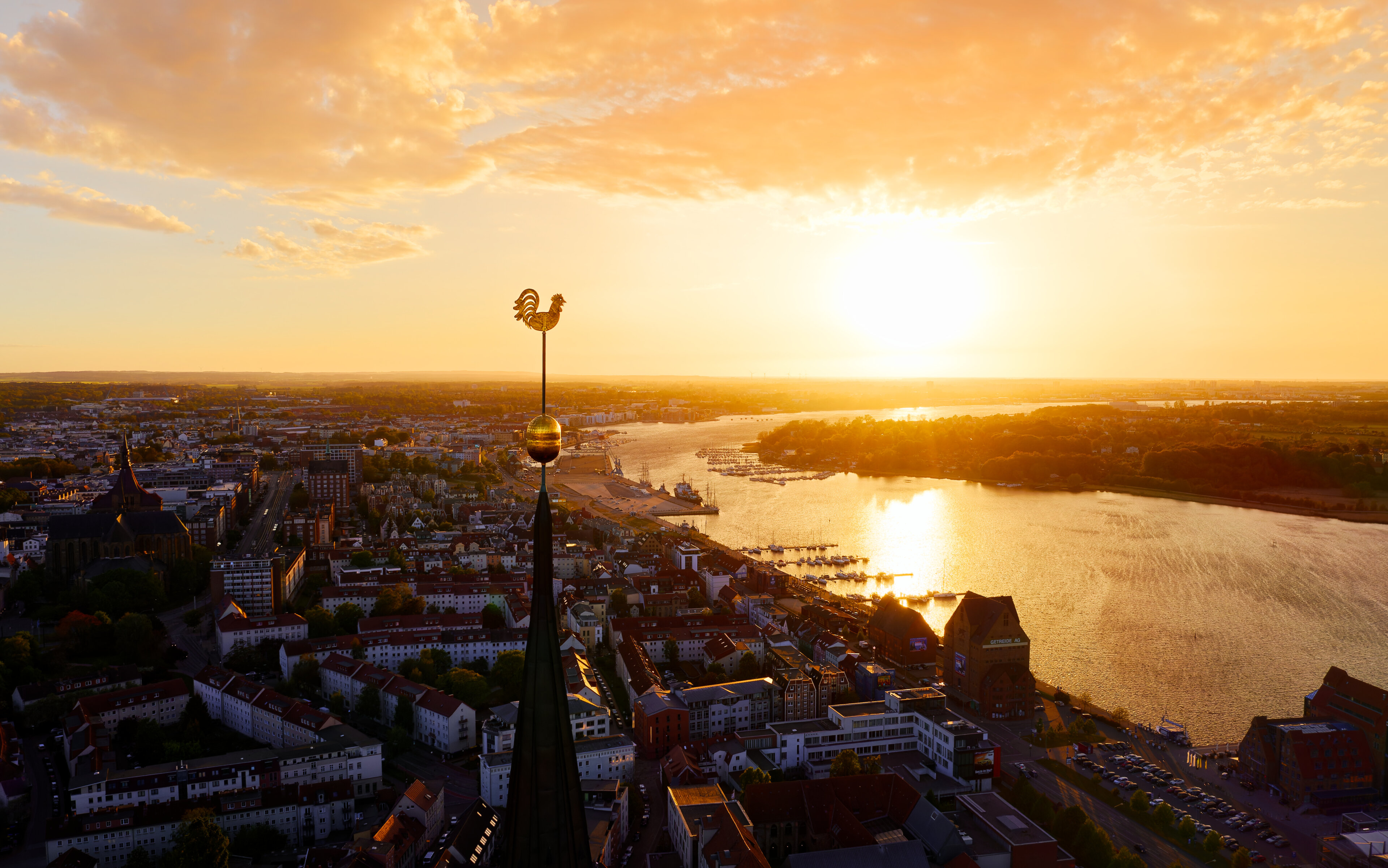 Goldener Hahn auf Petrikirche vor Sonnenuntergang im Rostocker Stadthafen